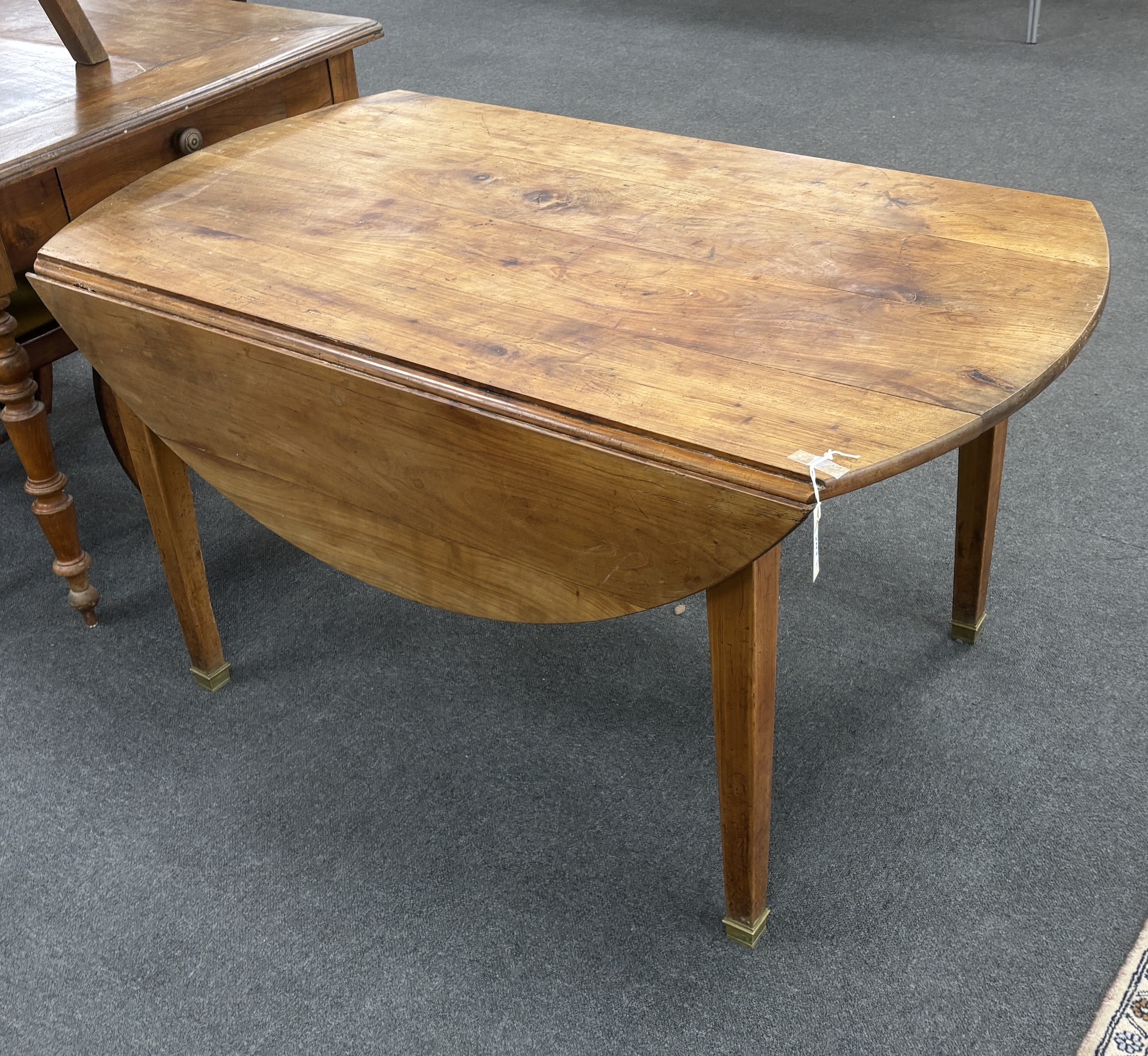 A 19th century French oval cherry drop flap kitchen table, width 136cm, depth 134cm extended, height 71cm